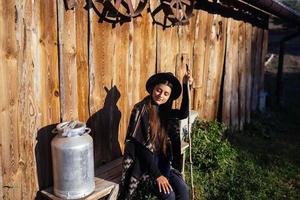 Woman sits on a bench with milk cans on a farm photo