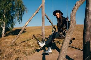 Young beautiful woman rides on a swing in the countryside photo