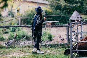 mujer joven cerca de un corral con ovejas en una granja foto