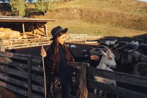 una mujer joven y hermosa cerca de un corral con cabras