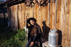 Woman sits on a bench with milk cans on a farm photo