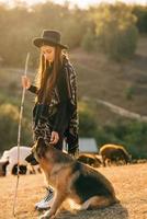 Female shepherd with a dog grazes a flock on the lawn photo