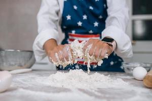 Young housewife in an apron kneads dough with her hands. photo