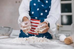 Young housewife in an apron kneads dough with her hands. photo