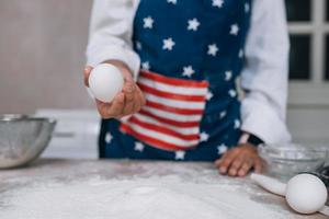 Girl confectioner holding chicken egg in her hand photo