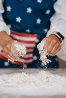 Young housewife in an apron kneads dough with her hands.