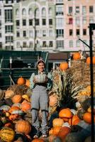 Happy farmer woman in a denim jumpsuit holds ripe pumpkin photo