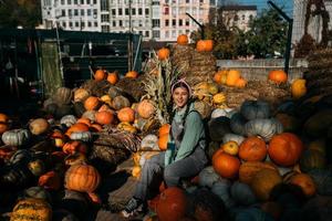 Young female farmer sits among a large number of pumpkins photo