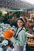 Happy farmer woman in a denim jumpsuit holds ripe pumpkin photo