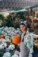 Happy farmer woman in a denim jumpsuit holds ripe pumpkin photo