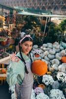 mujer granjera feliz en un mono de mezclilla sostiene calabaza madura foto