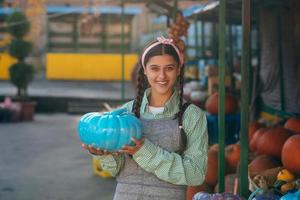 Female farmer holding blue colored pumpkin, decorated pumpkin for holiday. photo