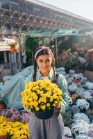 Woman holding decorative flower in flower pot on the market.