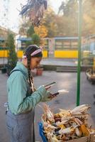 Young woman takes a photo of a corn cob at the market