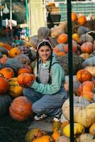 Farmer woman in a denim jumpsuit chooses ripe pumpkin photo