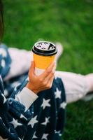 mano de mujer sosteniendo un vaso de papel de café en el parque foto