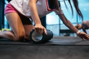 Young woman using a foam roller while doing stretching exercises photo