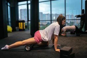 Young woman using a foam roller while doing stretching exercises photo