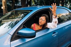 A young angry woman peeks out of the car window photo