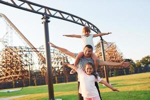 el padre se divierte con sus hijas en el parque de diversiones para niños durante el día foto