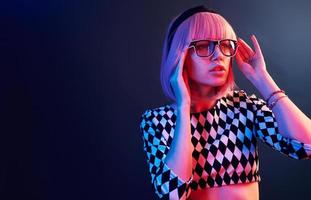 Portrait of young girl with blond hair in eyeglasses in red and blue neon in studio photo