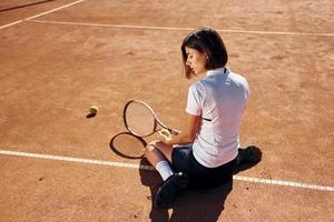 Rear view. Female tennis player is on the court at daytime photo