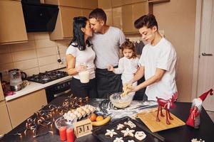 la familia feliz se divierte en la cocina y prepara la comida foto