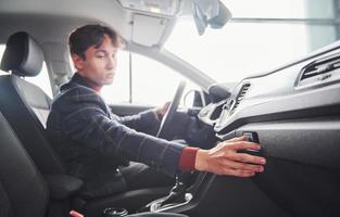 Guy in formal wear sitting inside of modern new car photo