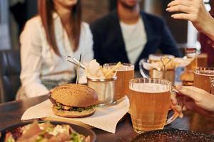 Eating and drinking. Group of young friends sitting together in bar with beer photo