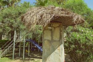 shower cubicle right on the beach. the shower is covered with natural branches and beige grass. washing after swimming in the salty sea. shower right on the beach photo