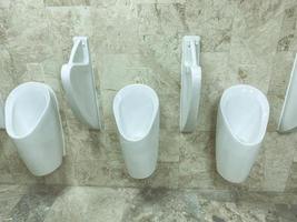 men's toilet. white faience urinals are fixed on the wall. there are partitions between the containers. plumbing in a public place photo