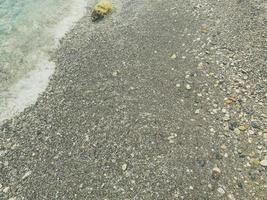 vacation by the sea on the beach. pebble beach with stones. on the shore lies a yellow stone, which is washed by the white waves of the sea with foam photo