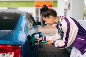 Woman filling her car with fuel at a gas station photo