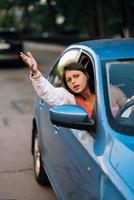 A young angry woman peeks out of the car window photo