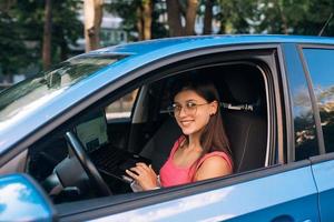 Young woman using laptop in her car while driving. photo