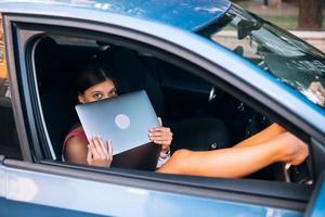 mujer joven que usa la computadora portátil en su coche foto