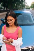 Woman using mobile phone near car at the street photo