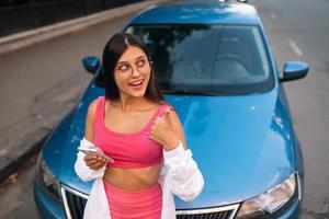 Woman using mobile phone near car at the street photo