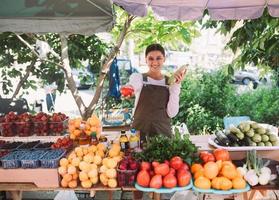 Young saleswoman holding zucchini and tomato in hands photo