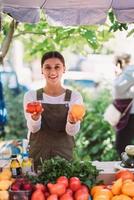 Young saleswoman holding home-grown tomatos in hands photo