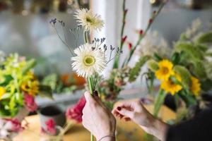 Florist woman makes a bouquet of fresh wildflowers photo