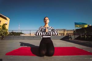 Woman doing yoga exercises on house roof in early morning photo