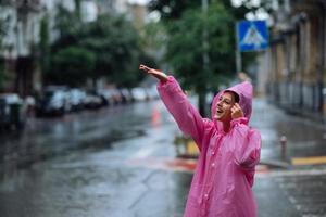 joven mujer sonriente con impermeable mientras disfruta de un día lluvioso. foto