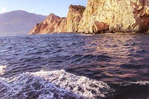 rock in the sea. blue expanse of water, sea surf, waves with white foam. a mountain of sand, stones, a gorge in the vast sea. seaside resort photo