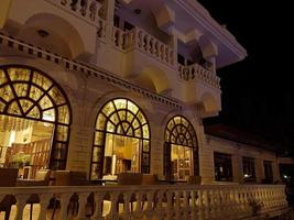 hotel in the evening. a whitewashed, tall, multistory building with carved windows and light. hotel with windows to the floor, evening view of the building photo