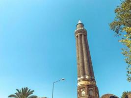 zona de un país cálido y tropical. torre alta con ventanas contra el cielo azul. torre con un alto chapitel de piedra. edificio de oficinas en un país cálido foto