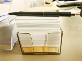 stationery on the table in the office. orange, transparent container for small notes. records of employees in the office photo