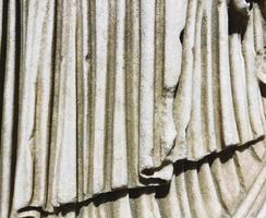 textura antigua. piedra beige, fondo voluminoso. una estatua con túnica, un trozo de tela de mármol. el fondo es blanco. revestimiento 3d, ondas de mármol foto