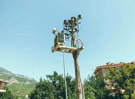 poste con línea eléctrica. bobinas eléctricas en cables negros, elementos de refrigeración. pilar contra el telón de fondo de una montaña en un país tropical cálido foto