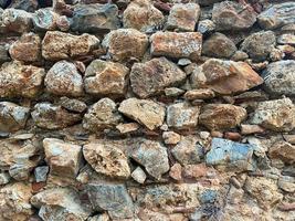 Background, texture, stone wall of round stones cobblestones bricks natural surface natural sharp convex rough stone cobblestone with cracks photo